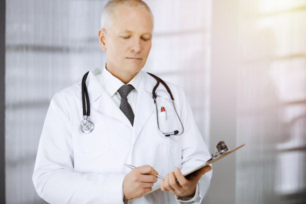 长者自信的医生站直和使用剪贴板在阳光诊所。完善的医疗服务。医学的概念图片下载