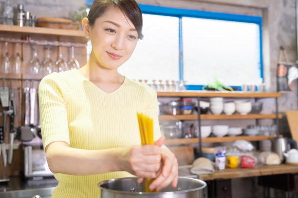 亚洲女人在厨房做饭，意大利面，图片下载