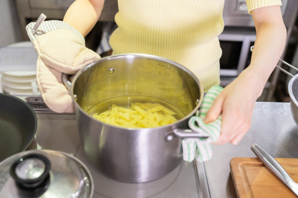 亚洲女人在厨房里做饭，意大利面，手图片下载