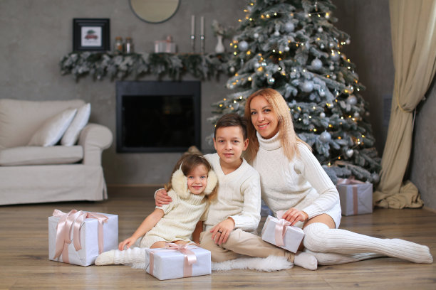 一家人——母亲、女儿和儿子，都穿着白色的针织衣服，庆祝新年、圣诞节。图片下载