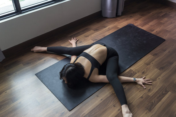 头顶上的女运动员在健身垫子上做伸展运动。图片下载