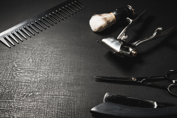 在黑色的表面上是老式的手动理发工具。图片下载