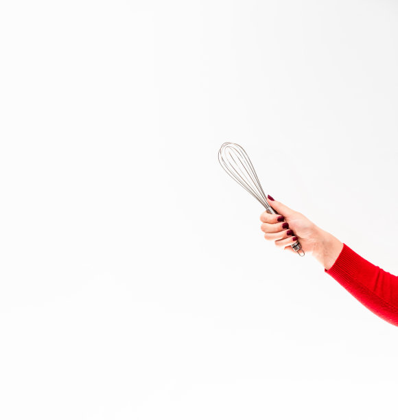 打蛋器用来在白色背景上用女性的手做甜点。文本空格。图片下载