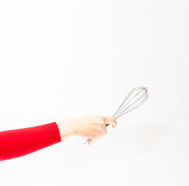 白色背景下，女孩手里拿着金属搅拌器。图片下载