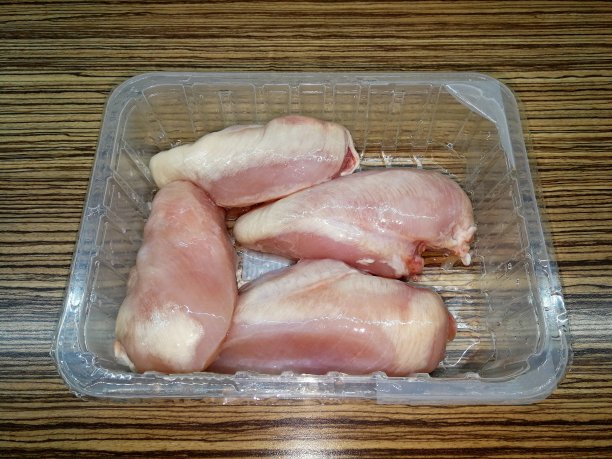 冷冻生鸡肉装在塑料容器里，放在木板上装饰木质图片下载
