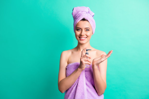 迷人可爱的女孩的照片，拿瓶子，喷雾器，洗手，戴紫罗兰，毛巾，头巾，孤立的，蓝绿色的背景图片下载