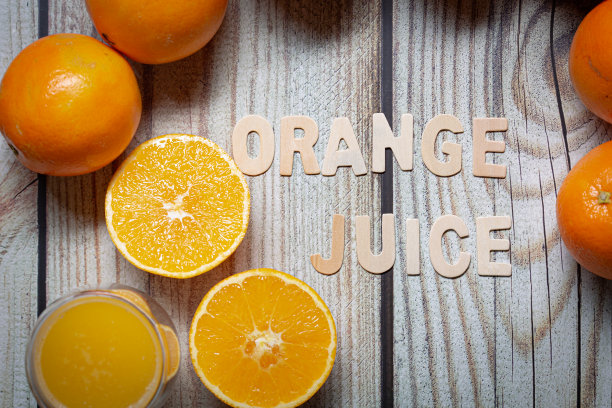 在一块木板上，橘子汁木拼字，周围是橘子水果图片下载