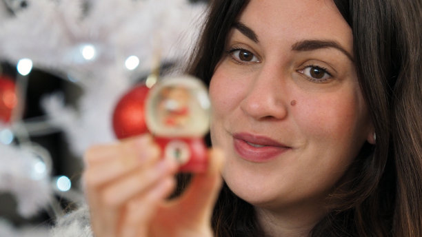 美丽的女孩坐在舒适的气氛中靠近圣诞树，拿着一份礼物。图片下载