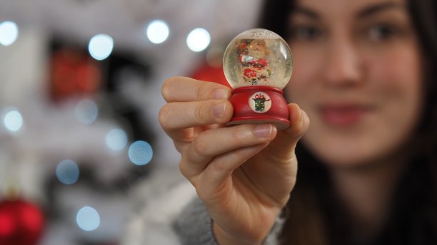 美丽的女孩坐在舒适的气氛中靠近圣诞树，拿着一份礼物。图片下载