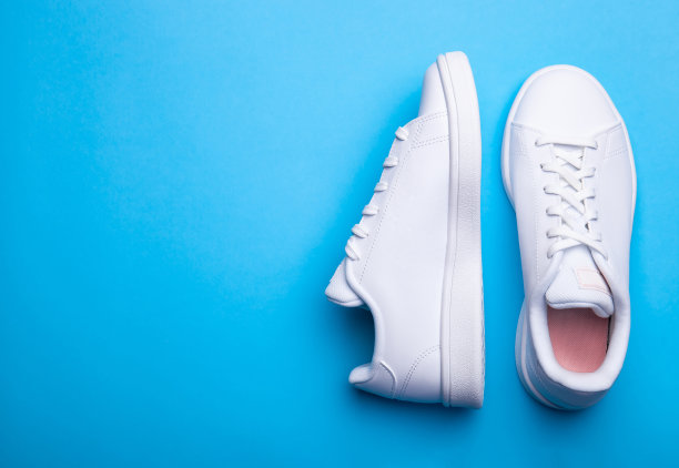 一双时尚的运动鞋在蓝色的背景。顶部视图的两个白色运动鞋的颜色背景与地方的文字图片下载
