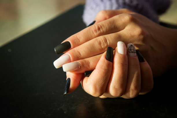女人的手近距离与黑白美甲，阳光照片。图片下载