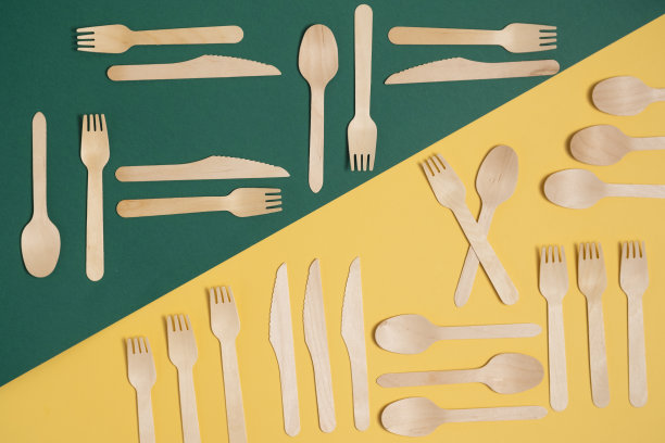 木制的叉子，刀和勺子在斜分开的绿色和黄色背景。图片下载