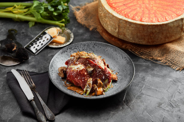 黑色的桌子上放着一盘有牛肉、烤牛肉、洋葱、芝麻菜、胡椒和西红柿的沙拉。俯视图图片下载