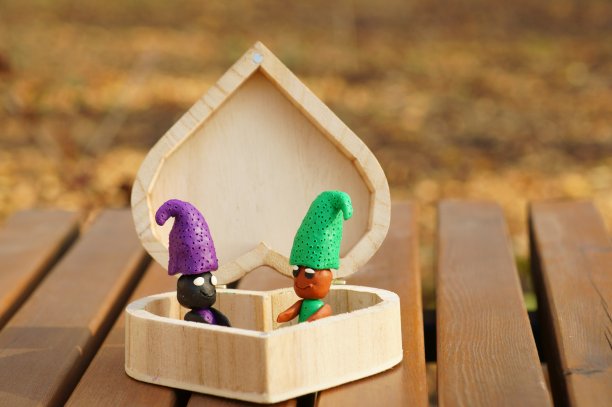 两个彩色的橡皮泥地精在一个木头盒子里。图片下载