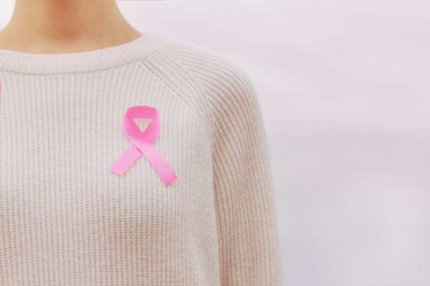 一张在白色毛衣上系着粉色丝带的妇女的照片，以支持与癌症的斗争图片下载