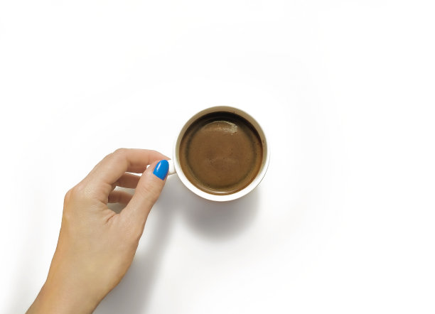 白色的咖啡杯在一个女性的手与一个蓝色的美甲孤立在白色的背景。俯视图图片下载