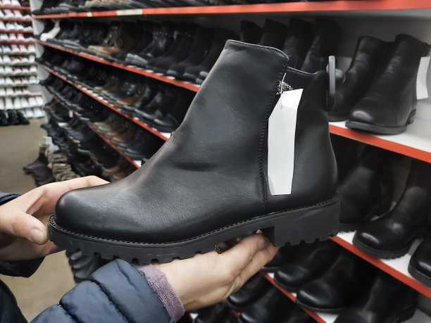 温暖的靴子在女人手中的商店里，女人挑选鞋子图片下载