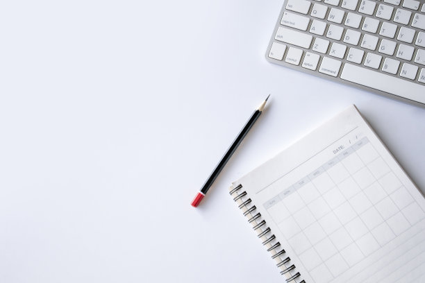 俯视图的办公室办公桌工作空间与打开的书，铅笔和键盘在白色的桌子背景。平躺图片下载