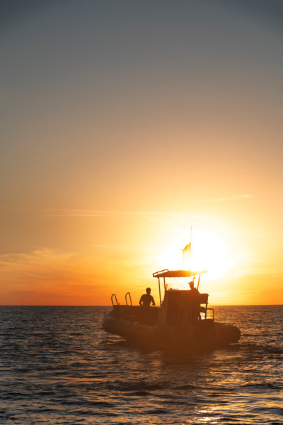 公海上日落时分一艘双体船的剪影图片下载