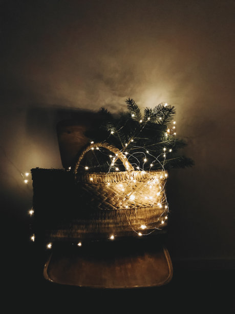 圣诞快乐!在黑暗中，木椅上挂着挂着圣诞树枝的乡村篮子图片下载