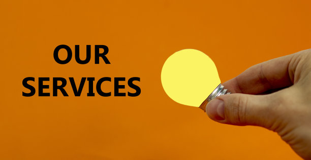 我们的服务的象征。商人手里拿着黄色的灯泡。理念与创新和灵感。“我们的服务”。美丽的橙色背景，复制空间。业务和我们的服务理念。图片下载