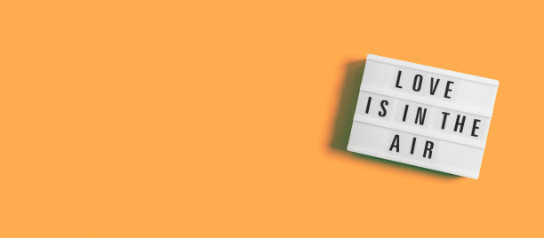 情人节的节日横幅与发光灯箱与文字的爱情是在空气中的橙色金盏花的背景。2月14日的Flatlay横幅。前视图。Copyspace。图片下载