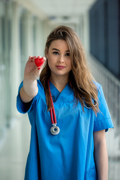 微笑漂亮的女医生在蓝色制服与听诊器抱心脏图片下载