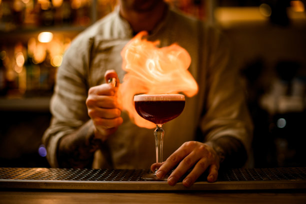 专业调酒师在酒杯上点燃泡沫鸡尾酒图片下载