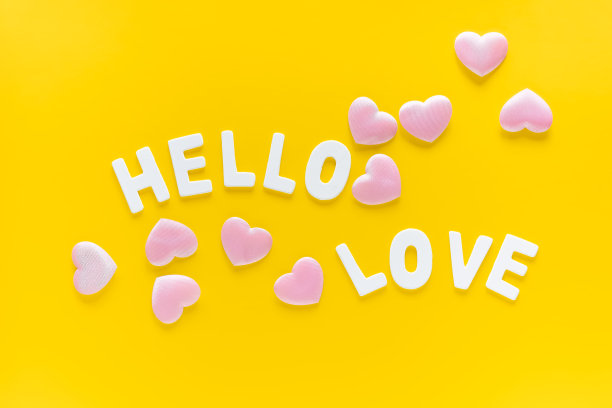 粉红色的心和在黄色背景上的白色木制字母“你好爱”的frase。情人节，母亲节，3月8日贺卡。平的。图片下载