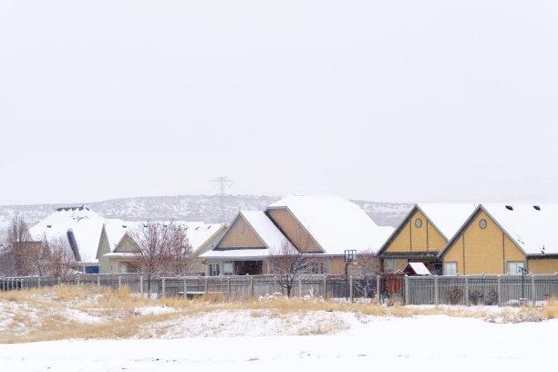 在寒冷的冬日里，小山和阴云密布的天空映衬着白雪皑皑的屋顶图片下载