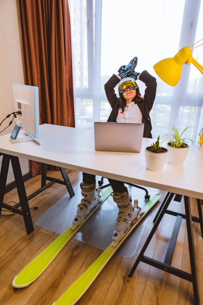 穿着滑雪装备在办公室用笔记本工作的女人图片下载