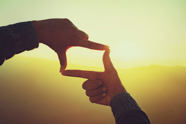 女人的手框架远景日落。经营理念图片下载