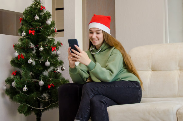 女孩在手机上读圣诞短信，通过电话在线祝贺新的短信图片下载