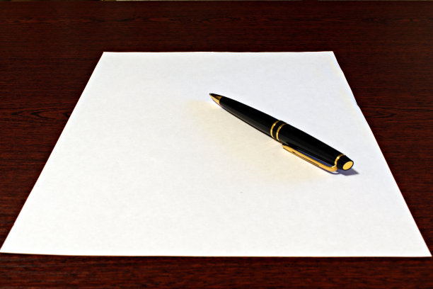 黑色镀金的高级圆珠笔在白纸上图片下载