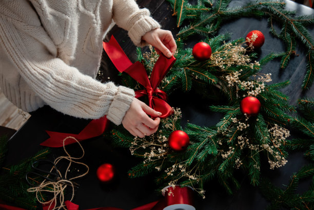 女孩自己在家里的桌子上装饰圣诞花环图片下载