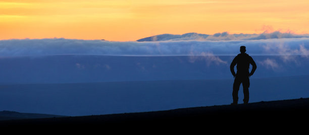 徒步旅行者站在壮观的蓝色分层山脉剪影。冰岛的日落景观。图片下载
