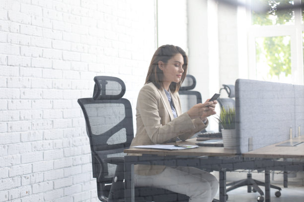 透过玻璃拍摄的年轻商务女性在办公室使用智能手机的照片。图片下载