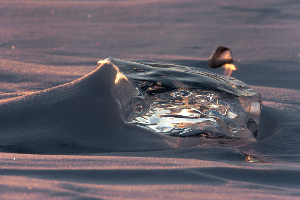 美丽的发光的冰块在夕阳下的雪图片下载
