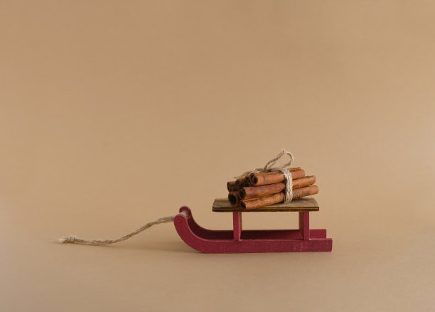 用肉桂棒装饰的红色木制雪橇。颜色柔和的背景。副本的空间。冬季和圣诞节贺卡设计模板。图片下载