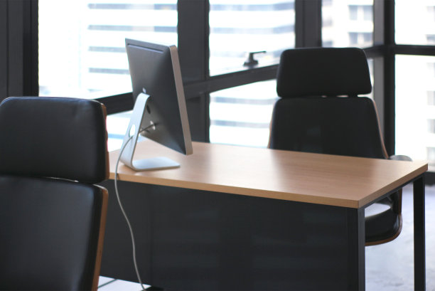 有选择地专注于带有大窗户背景的办公空间的木桌桌图片下载