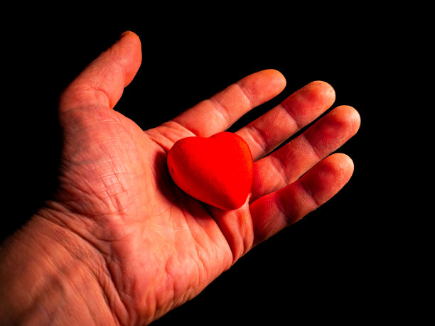 心形象征情人节手在黑色的背景。图片下载