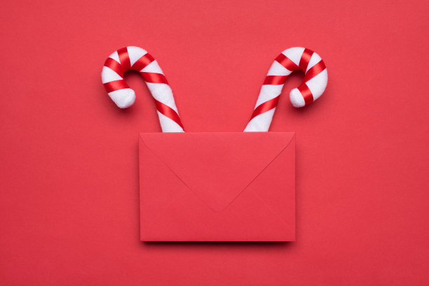 圣诞节组合的概念。上面的近距离查看照片图像的信封与角的形状硬焦糖甘蔗孤立柔和的颜色背景图片下载