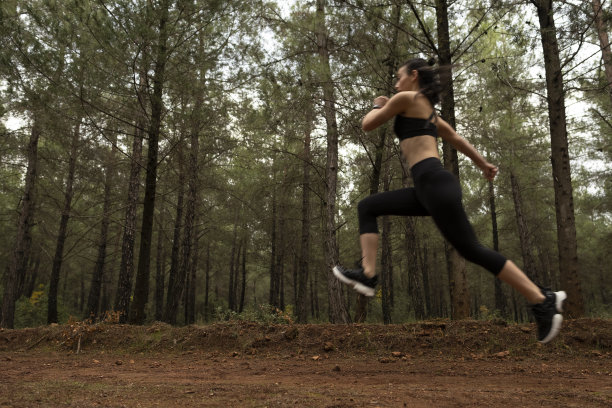 年轻的女运动员在森林里慢跑。晨跑者做体能训练。图片下载