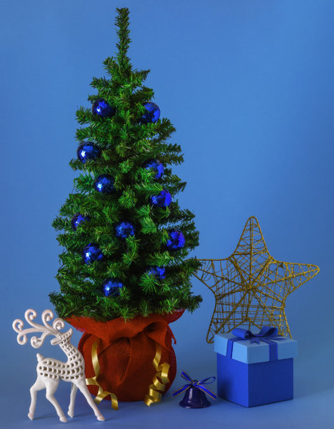 圣诞树上有驯鹿、礼盒、铃铛、星星和蓝色背景的装饰品图片下载