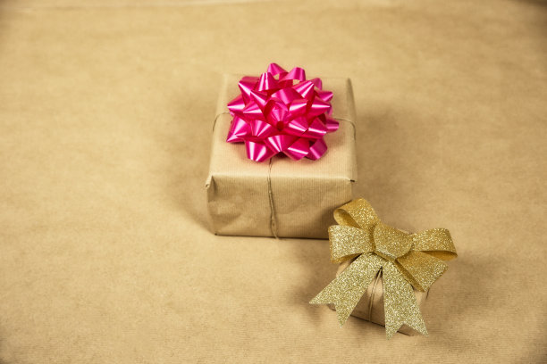 两个盒子在生态棕色普通纸与金色和粉红色包装装饰，生日礼物，情人节母亲节和其他政党的概念在棕色背景顶视图图片下载