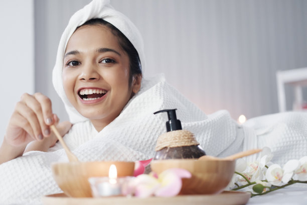 微笑的亚洲妇女在白色头巾和浴巾躺下和放松在床上准备按摩治疗在泰国的替代医学治疗水疗中心图片下载