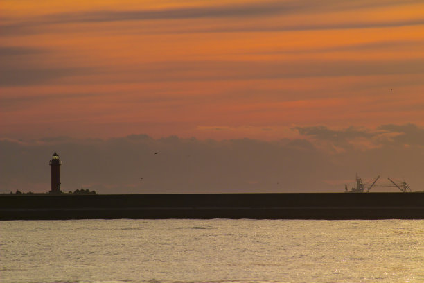 钏路港灯塔的剪影投射在日落时的橙色天空中图片下载