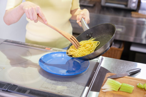 亚洲女人在厨房里做饭，意大利面，手图片下载