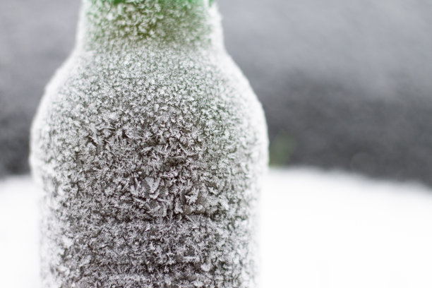 半模糊的啤酒瓶覆盖着白霜的雪在黑暗的背景。本空间图片下载