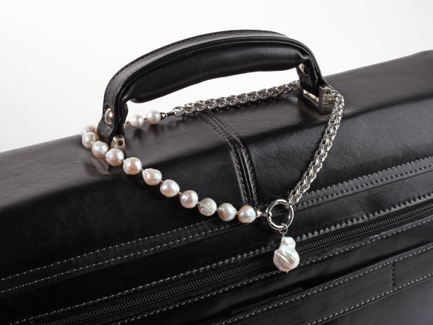 女人的银色巴洛克珍珠项链垂饰在男性的黑色皮箱图片下载